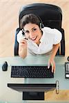 Cheerful call center agent looking at camera while on a call in her workplace