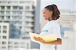 Cheerful altruist woman holding notebook outdoors on urban background