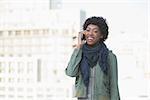 Smiling casual model on the phone outdoors on a sunny day