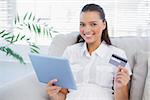 Smiling cute woman buying online using her tablet pc in bright living room