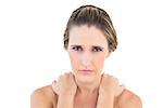 Frowning woman looking at camera with sore shoulders against white background