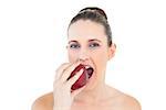 Pretty woman eating apple looking at camera against white background