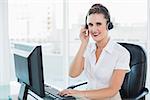 Happy call centre agent sitting on swivel chair in bright office