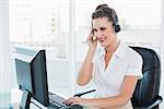 Cheerful call centre agent working on computer while having a call in bright office