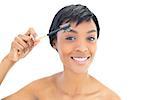Happy black haired woman brushing her eyebrows on white background