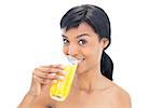 Dynamic black haired woman drinking orange juice on white background