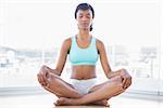 Meditative black haired woman doing yoga in a living room