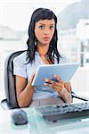 Stern businesswoman using a tablet pc in office