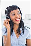 Pleased operator adjusting her headset in office