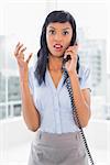 Angry businesswoman answering the phone in office