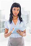 Unsmiling businesswoman using a tablet pc in office