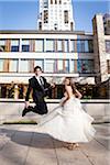 Bride and Groom jumping and having fun posing in City Park on Wedding Day, Toronto, Ontario, Canada