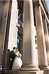 Portrait of Bride and Groom posing outdoors on Wedding Day in front of Pillars on building entrance, Toronto, Ontario, Canada