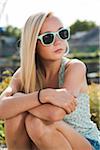 Portrait of teenage girl sitting outdoors, wearing sunglasses and looking to the side, Germany