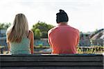 Backview of teenage girl and teenage boy sitting on bench outdoors, Germany