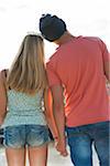 Backview of teenage boy and teenage girl holding hands, standing outdoors, Germany