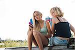 Teenage girls sitting on bench outdoors, looking at cell phone, Germany