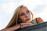 Portrait of teenage girl sitting on bench outdoors, looking into the distance, Germany