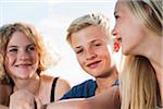 Close-up portrait of teenage girls and boy sitting outdoors, Germany