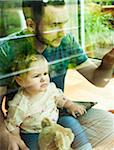 Baby Girl sitting on Father's Lap at Home, Mannheim, Baden-Wurttemberg, Germany