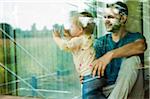 Baby Girl and Father Looking out Window at Home, Mannheim, Baden-Wurttemberg, Germany