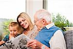 Young Woman with Baby Girl and Senior Man looking at Photo Album, Mannheim, Baden-Wurttemberg, Germany