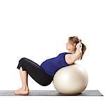 Young pregnant woman exercising with fitness ball,  studio shot