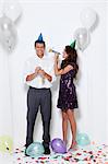 Young couple blowing horns at party