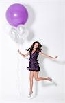 Young woman holding balloons, floating at party