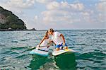 Dressed up man and woman riding paddle boards