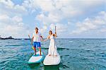 Dressed up man and woman riding paddle boards