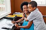 Woman working at home office with son