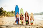 Family standing on beach with surfboards