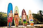 Family of four standing in front of surfboards