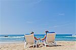 Rear view of couple in beach chairs