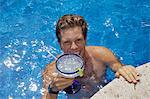 Young man in pool holding cocktail