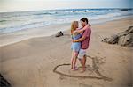 Young couple standing in heart design on beach