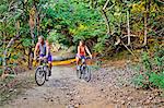 Couple riding bicycles on jungle path