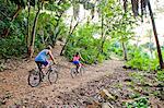 Couple riding bicycles on jungle path