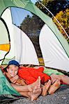 Young boy's face and pairs of feet poking out of tent