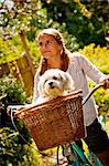 Teen girl on bike with dog in basket