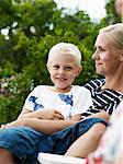 Mother and boy sitting in outdoor chair