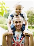 Teenage boy carrying younger brother on shoulders