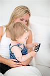 Little girl sitting on mothers lap and holding cell phone