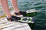 Person wearing diving flippers on jetty, close-up