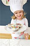 Little girl with chef's hat presenting muffins, Munich, Bavaria, Germany