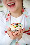 Little girl holding colorful muffin, Munich, Bavaria, Germany