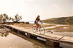 Croatia, Dalmatia, Young woman at the seaside, riding a bike