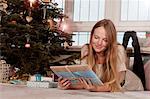 Woman with blond hair holidng gift box next to Christmas tree, Munich, Bavaria, Germany