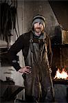 Blacksmith standing in workshop, forge in background, Landshut, Bavaria, Germany